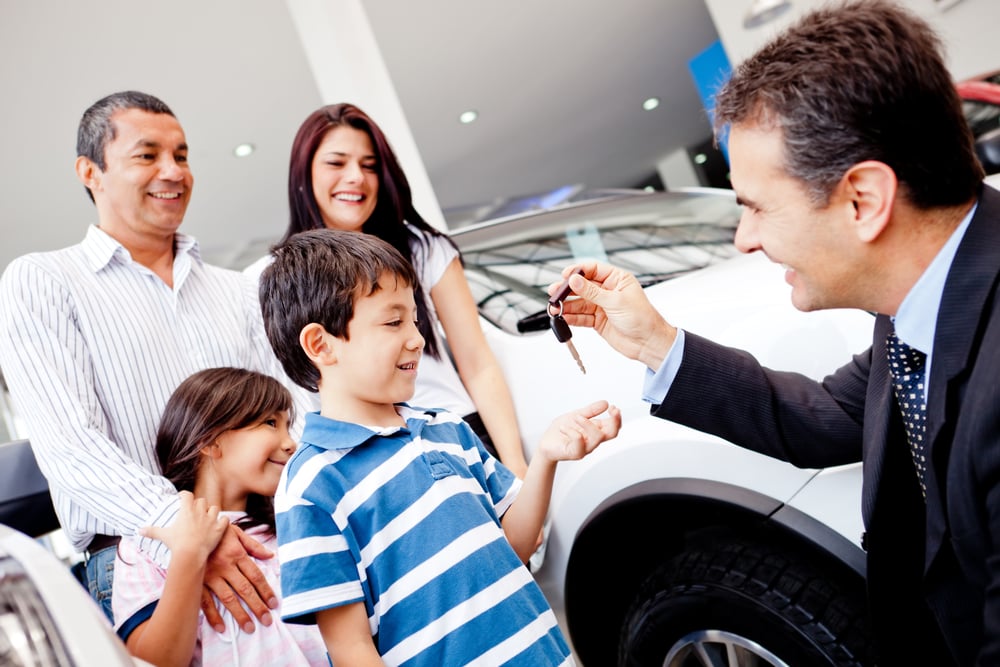 Family buying a new car and getting the keys from salesman