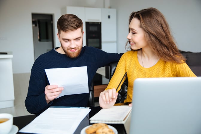 Happy young couple calculating bills at home